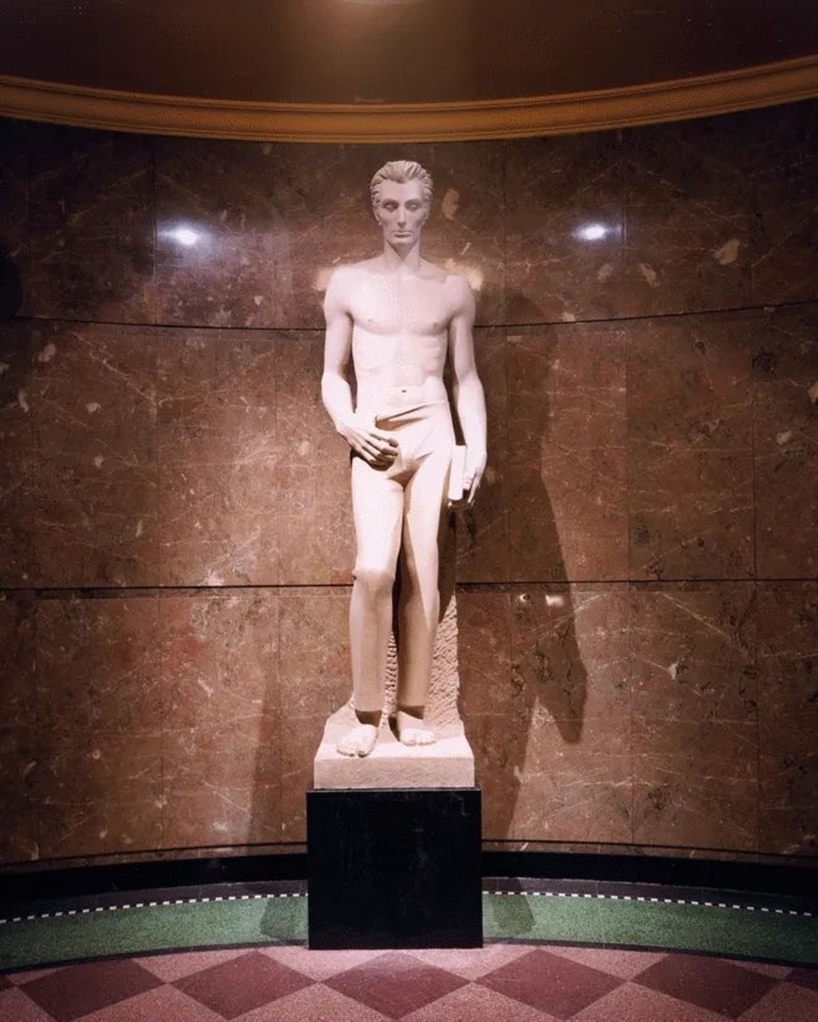 A statue of Lincoln topless and sinewy with his thumb hooked into the top of his pants.