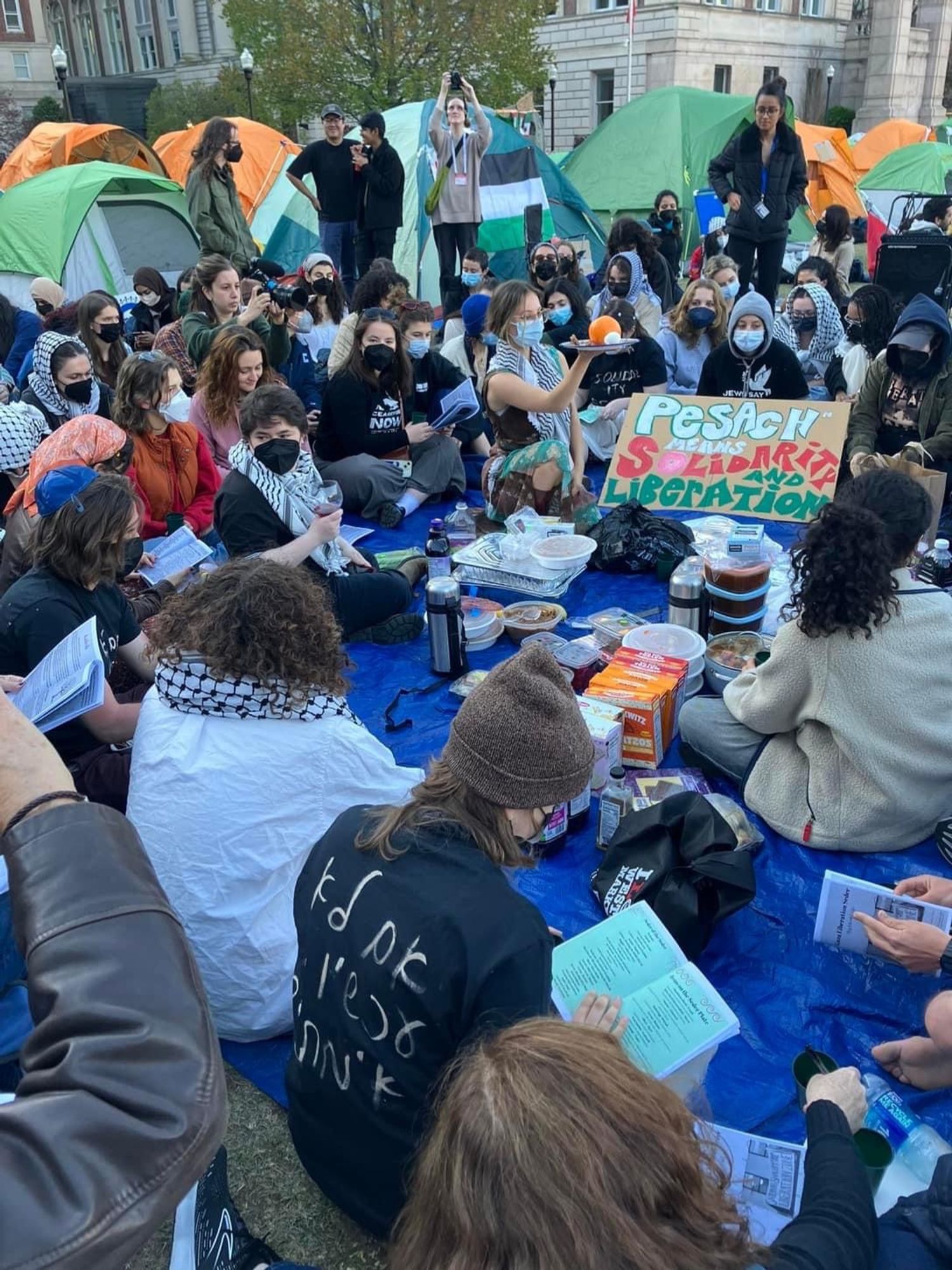 A group of students protesting at Columbia, sitting in their outdoor encampment and celebrating Passover.