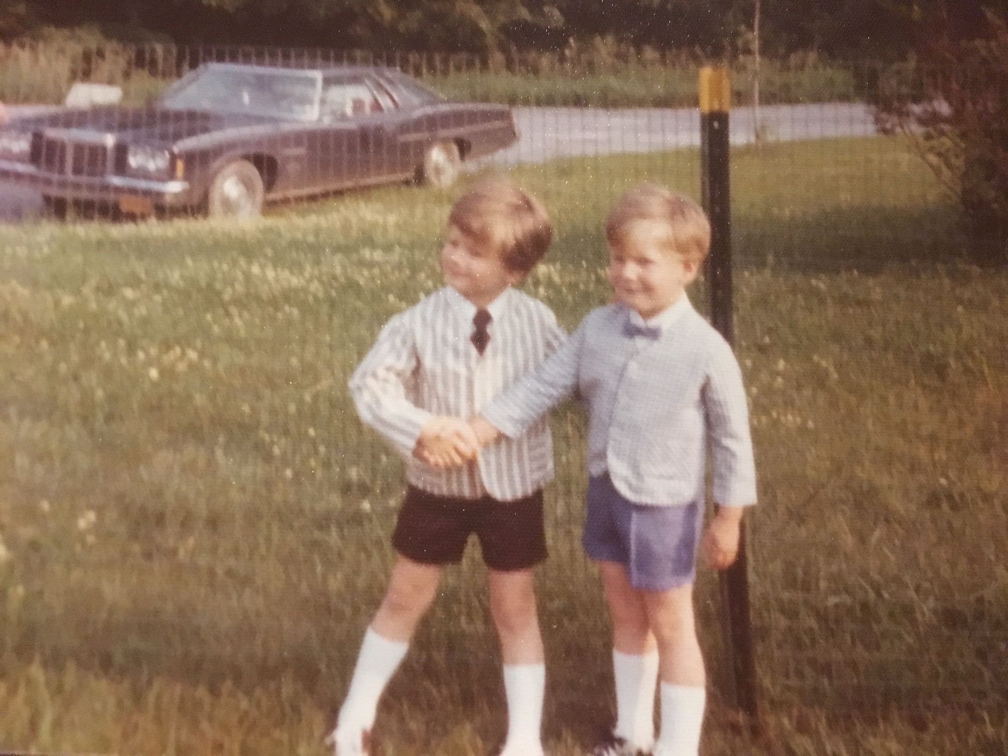 Two young boys- either 3 and 4 or 4 and 5 - at Easter. They are wearing seersucker jackets with coordinating shorts and neckties, calf-high tube socks, and saddle shoes- almost certainly Buster Browns.