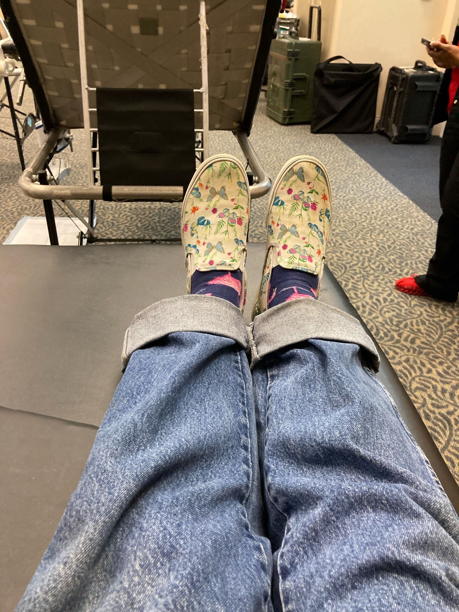 A pair of very stylish kicks with butterflies on them, currently laid out on a Red Cross donation bed.