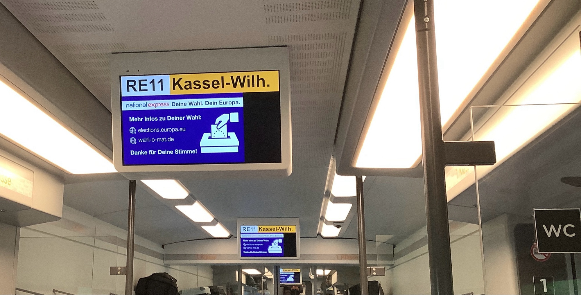 Zuganzeiger im Wagon Text

RE11 Kassel-Wilh.
national express Deine Wahl. Dein Europa.
Mehr Infos zu Deiner Wahl:
elections.europa.eu
wahl-o-mat.de
Danke für Deine Stimme!
symbolbild Hand wirft Wahlzettel in Wahlurne