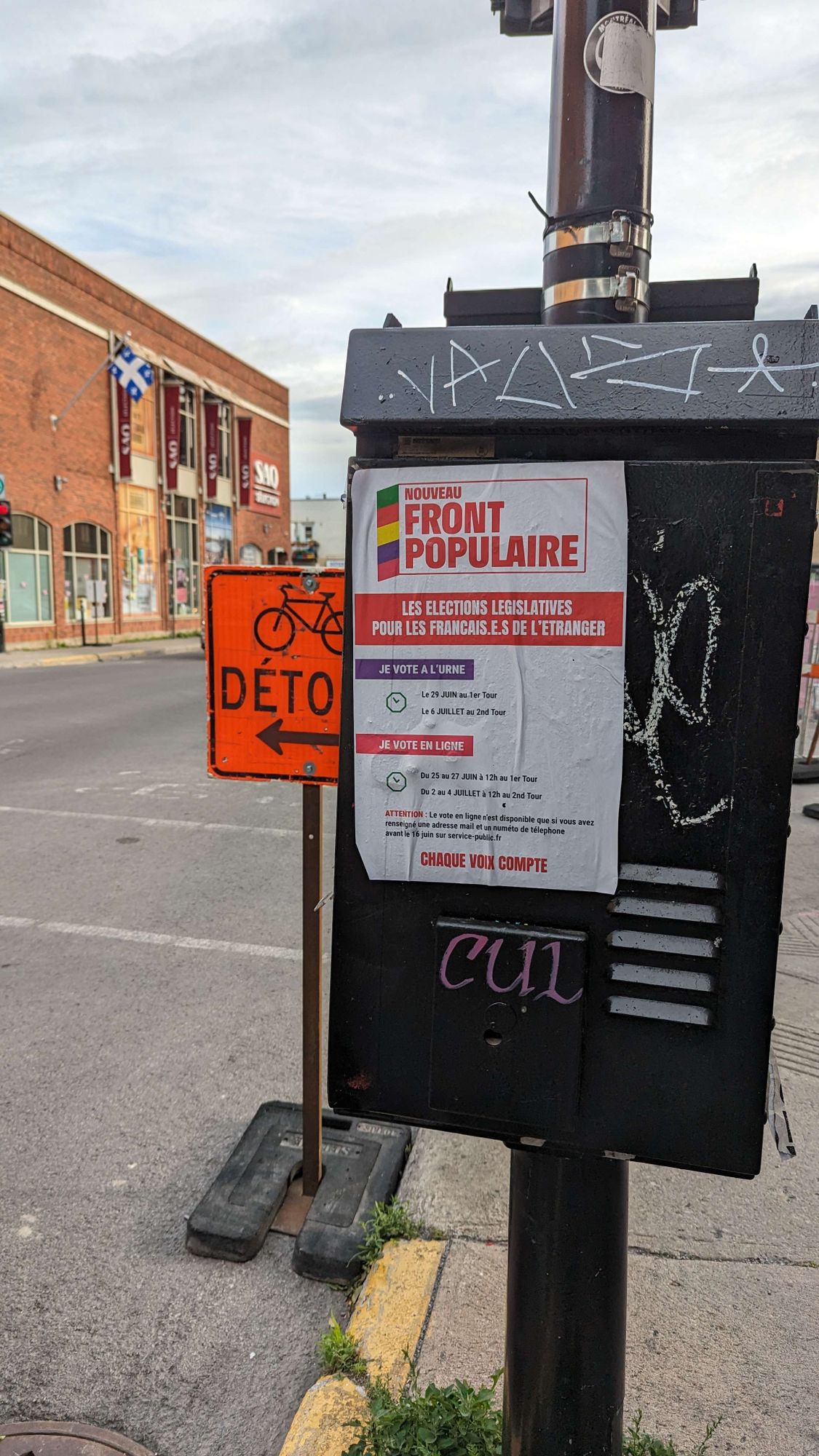 Une affiche du  Nouveau Front Populaire sur un poteau de la rue Beaubien à Montréal. Au fond, une SAQ.