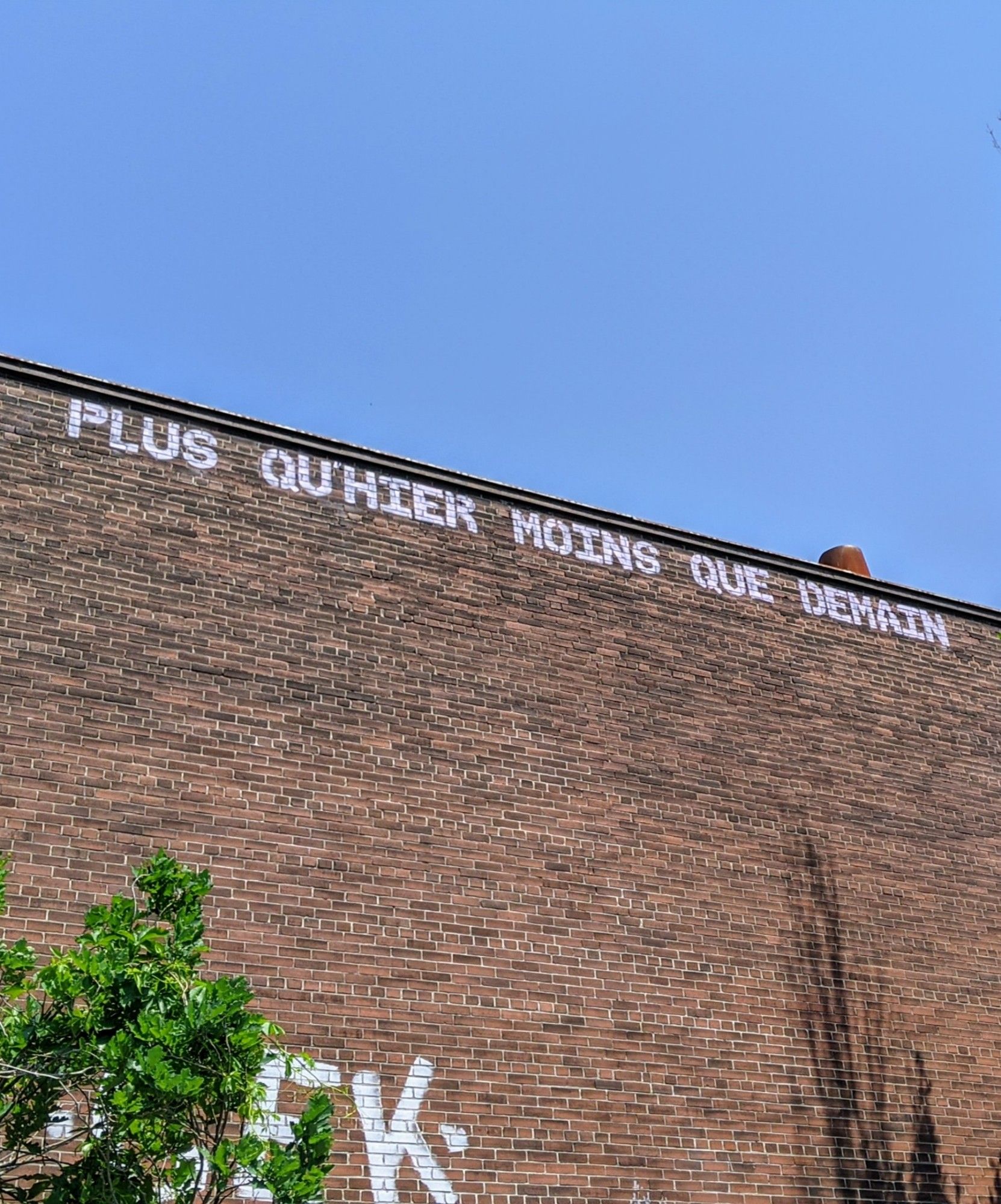 Sur un mur de briques à Montréal : "Plus qu'hier moins que demain"