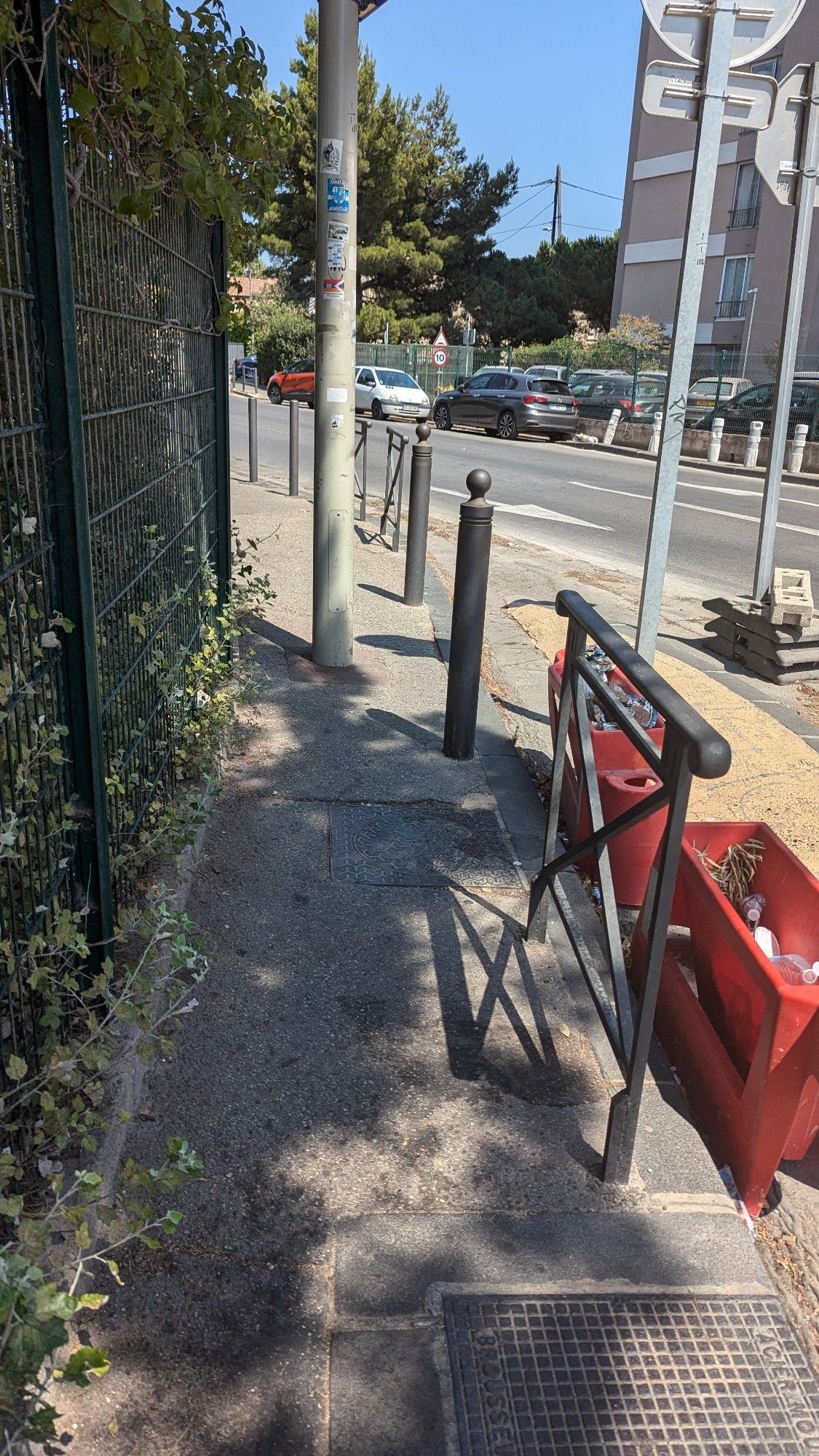 Un trottoir étroit, avec un poteau en plein milieu, gênant le passage.