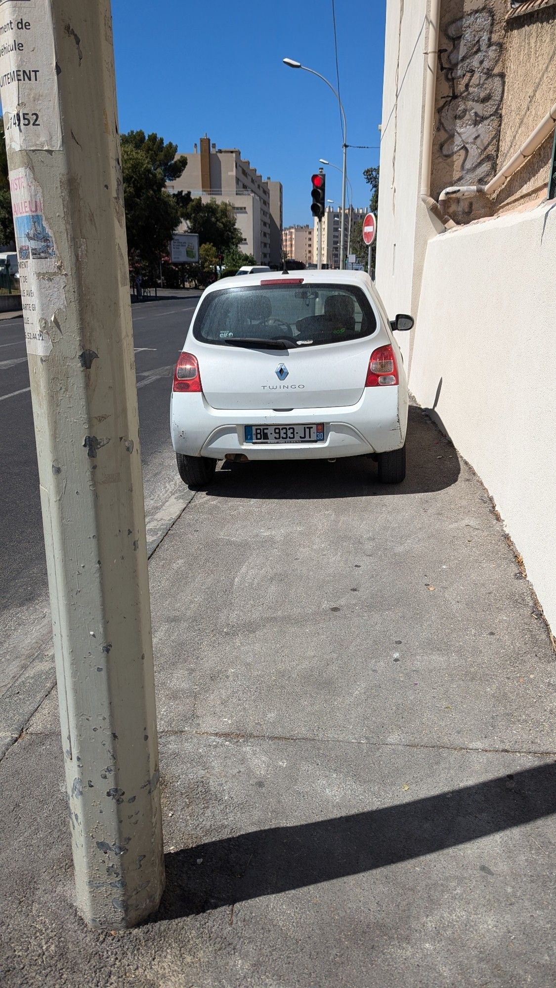 Un trottoir bloqué par une voiture mal stationnée.