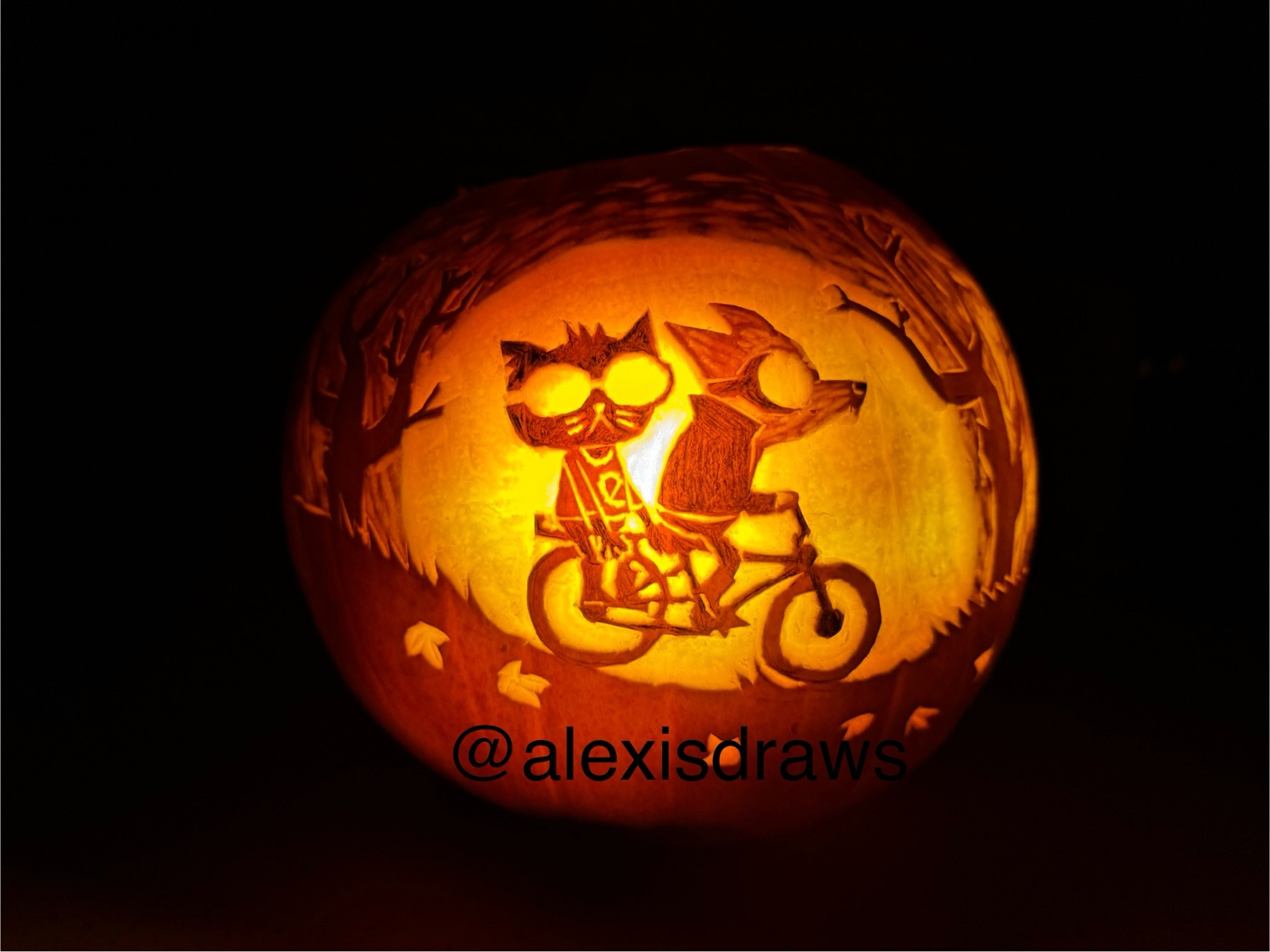 A lit Halloween pumpkin carved with an image from the game Night in the Woods, showing Gregg and Mae riding a bike