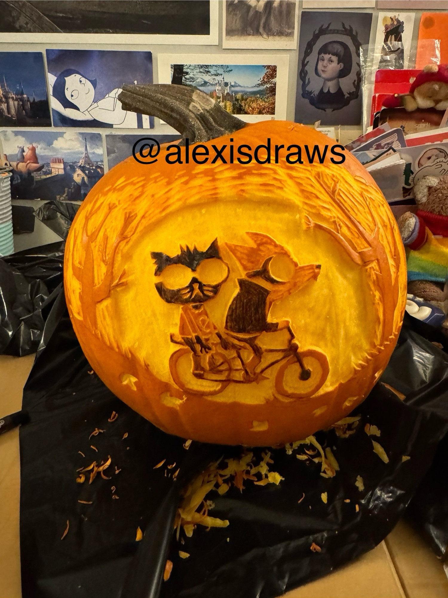 An unlit Halloween pumpkin carved with an image from the game Night in the Woods, showing Gregg and Mae riding a bike