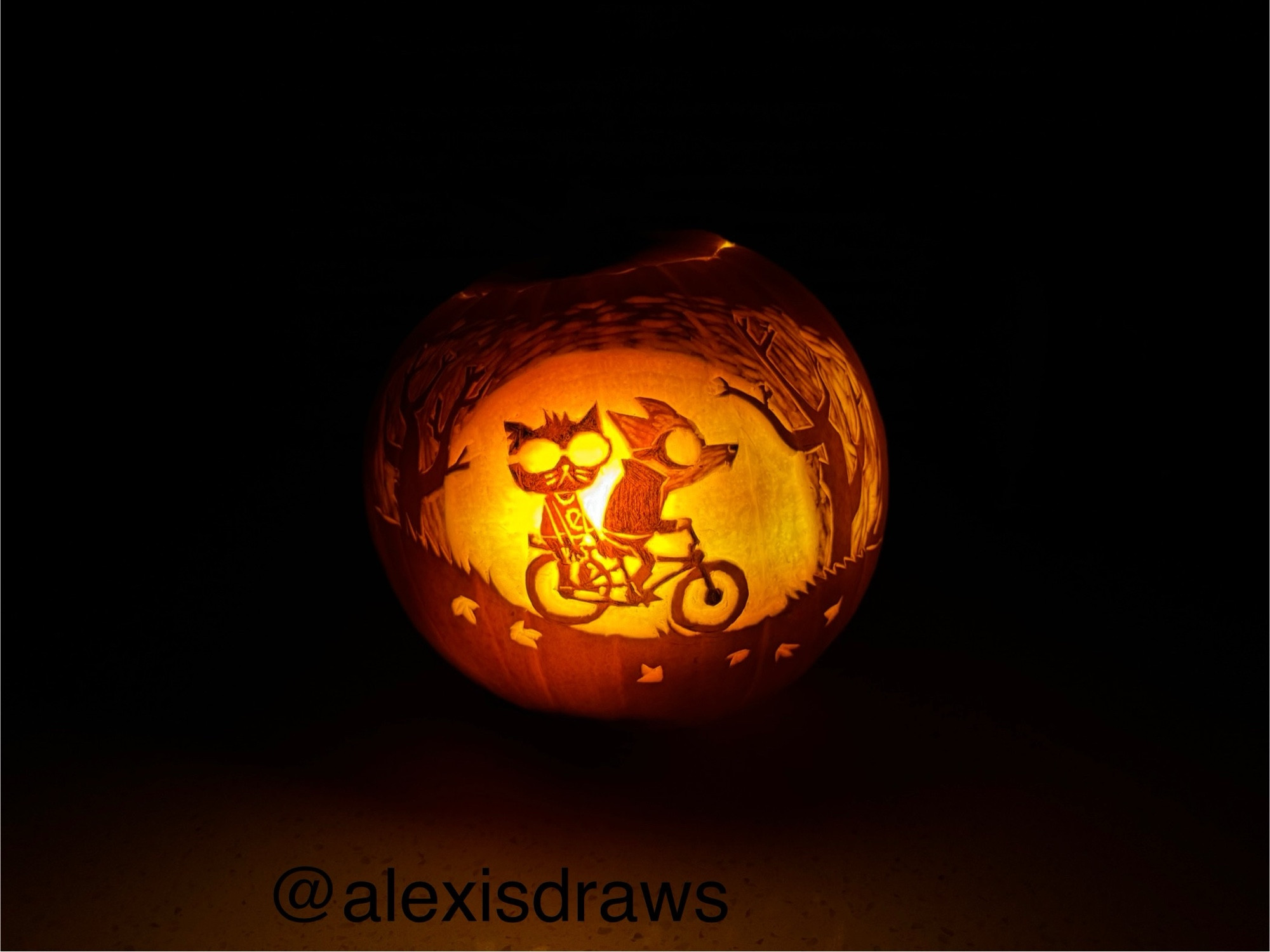 A lit Halloween pumpkin carved with an image from the game Night in the Woods, showing Gregg and Mae riding a bike