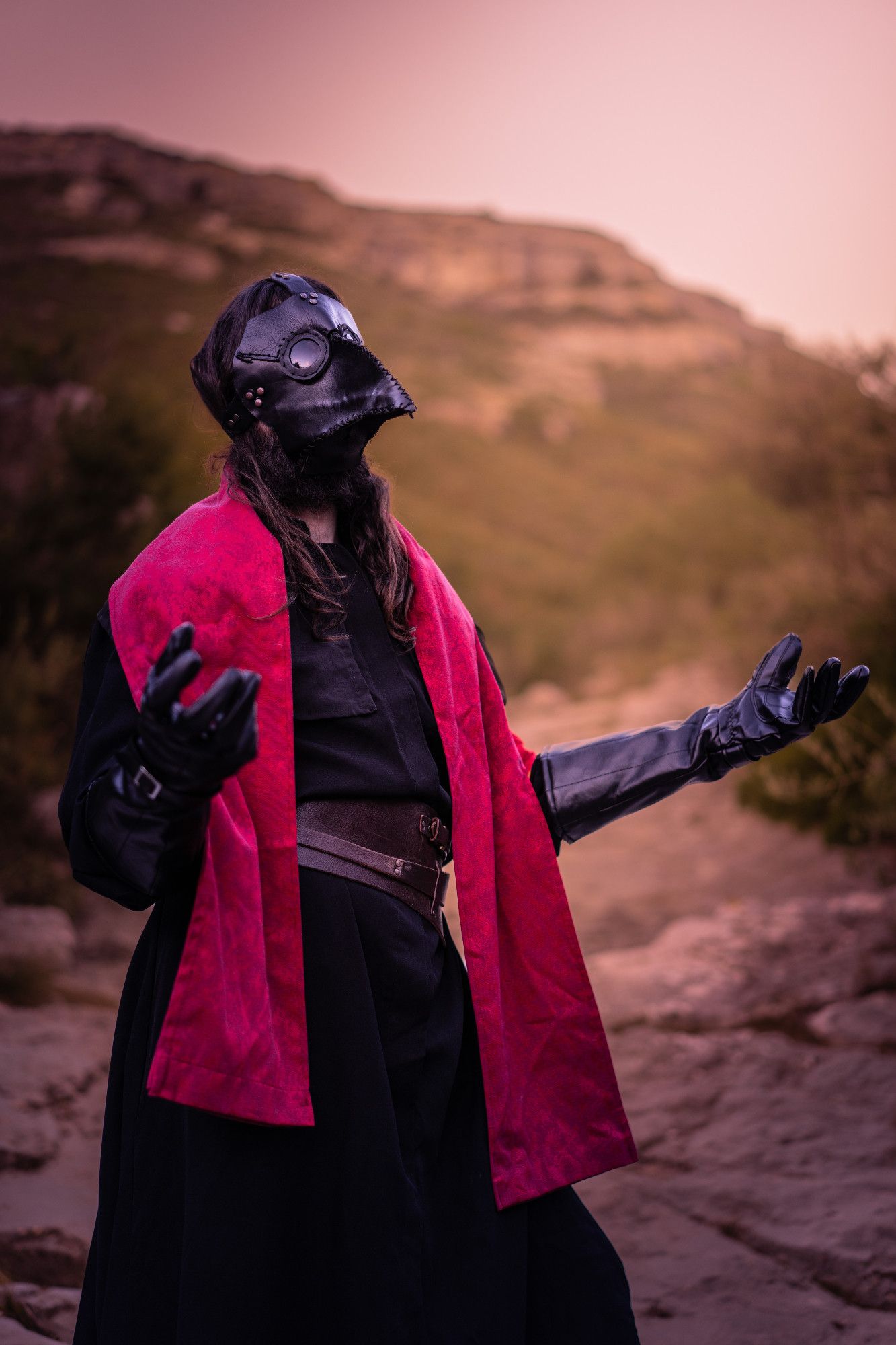 Photo of a plague doctor dressed in black with a red scarf, in a proud pose