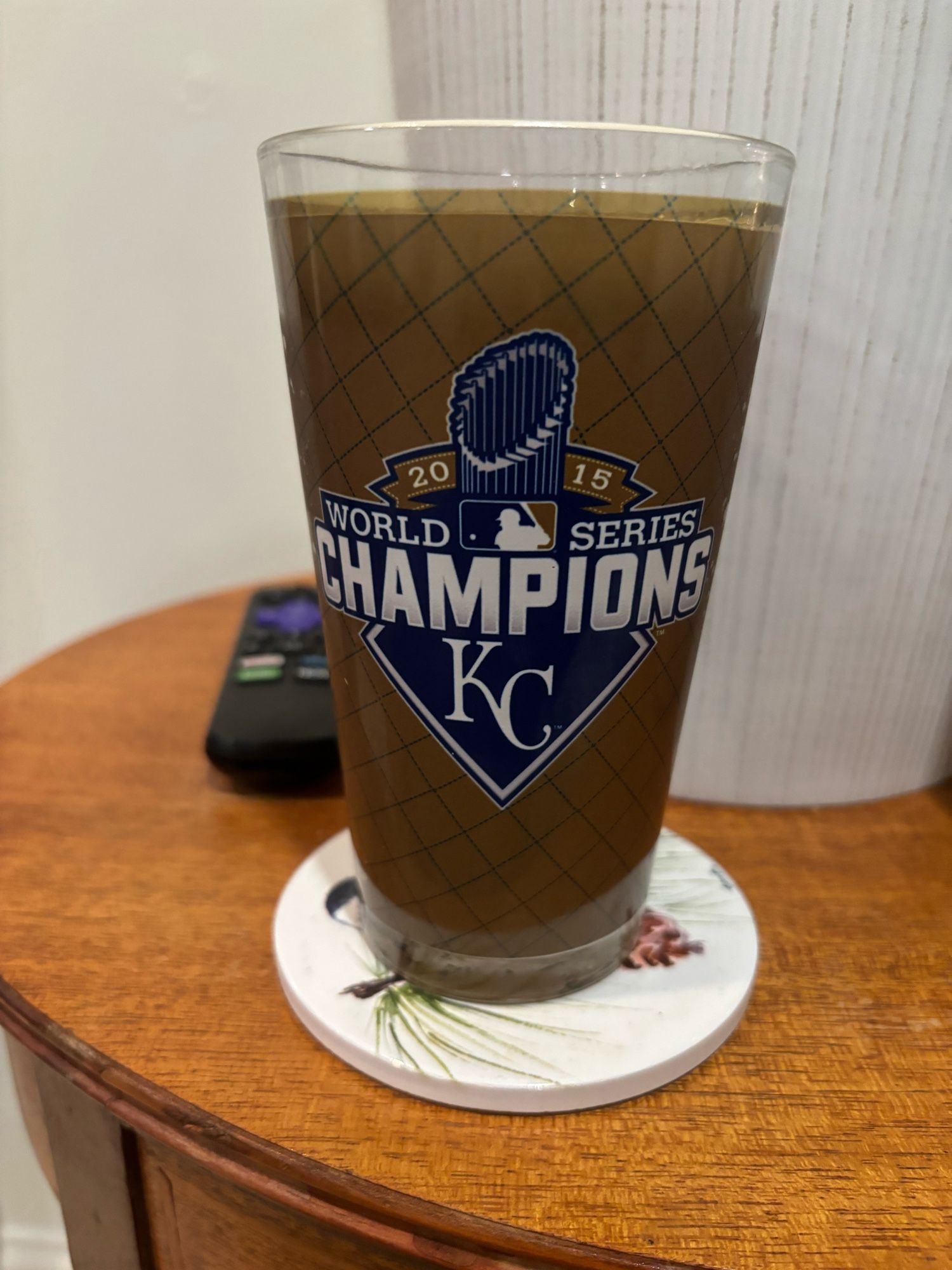 A 2015 World Series Champions glass for the Kansas City Royals, filled with Warren G Double IPA from The Guild brewery in Rhode Island. A blurry Roku remote sits behind it.