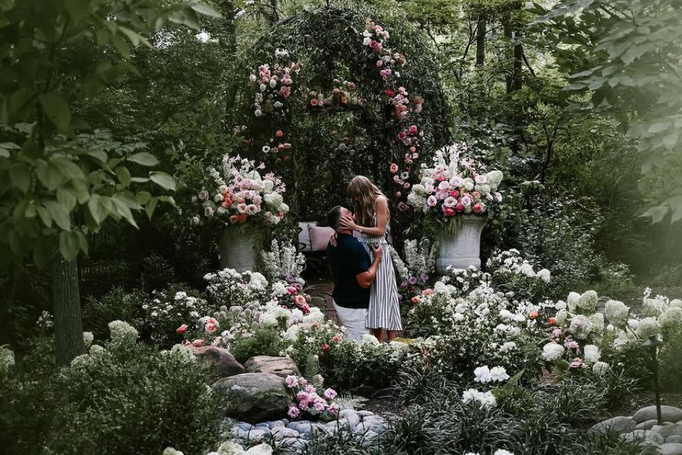 Travis Kelce and Taylor Swift during their proposal in a garden of flowers 