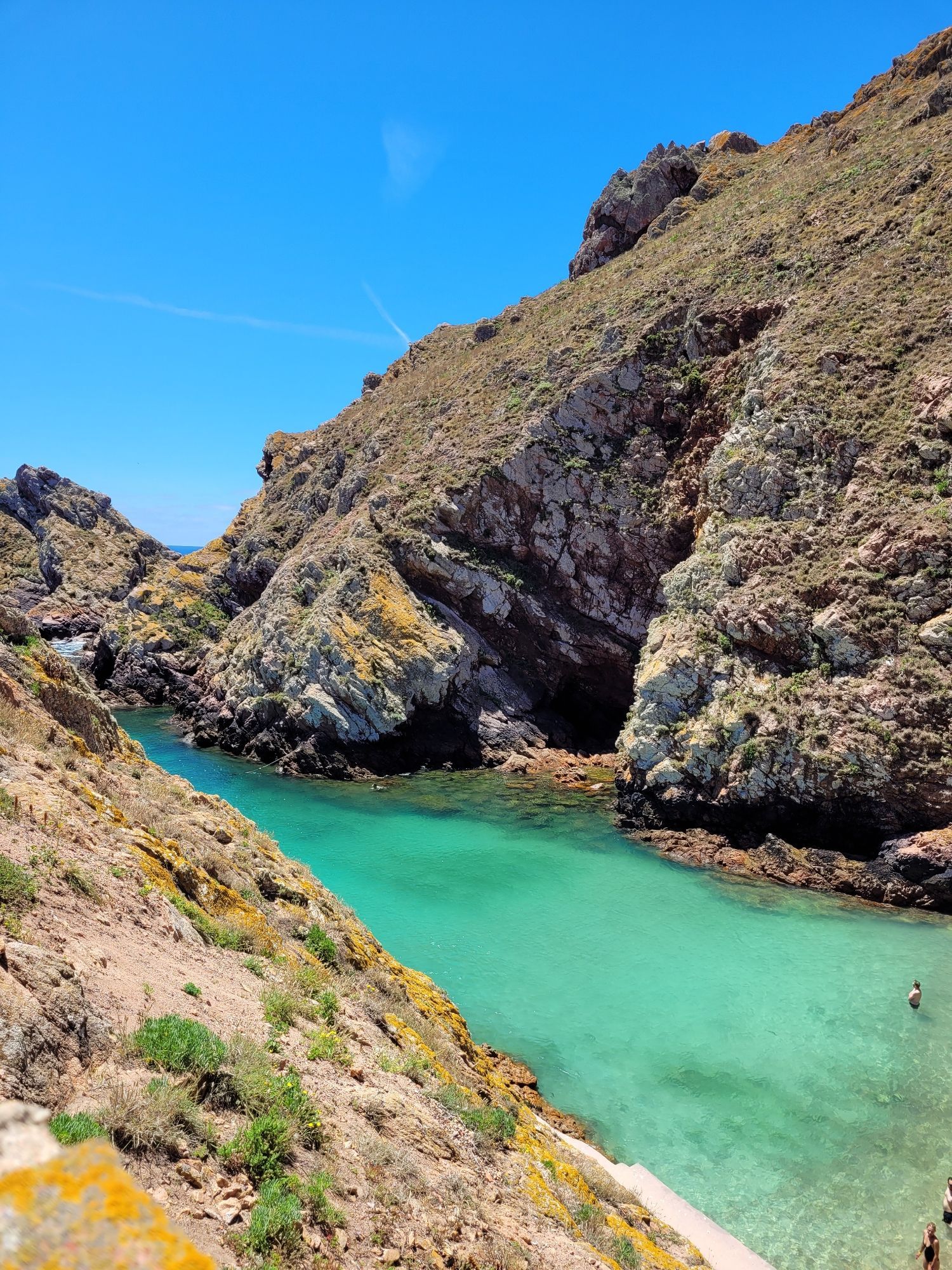 Man sieht mit schrägem Blick auf eine Bucht. Links und rechts sind hohe, steile Felsenwände. In der Mitte sieht man wunderbar grünblaues Wasser, das extrem klar ist.