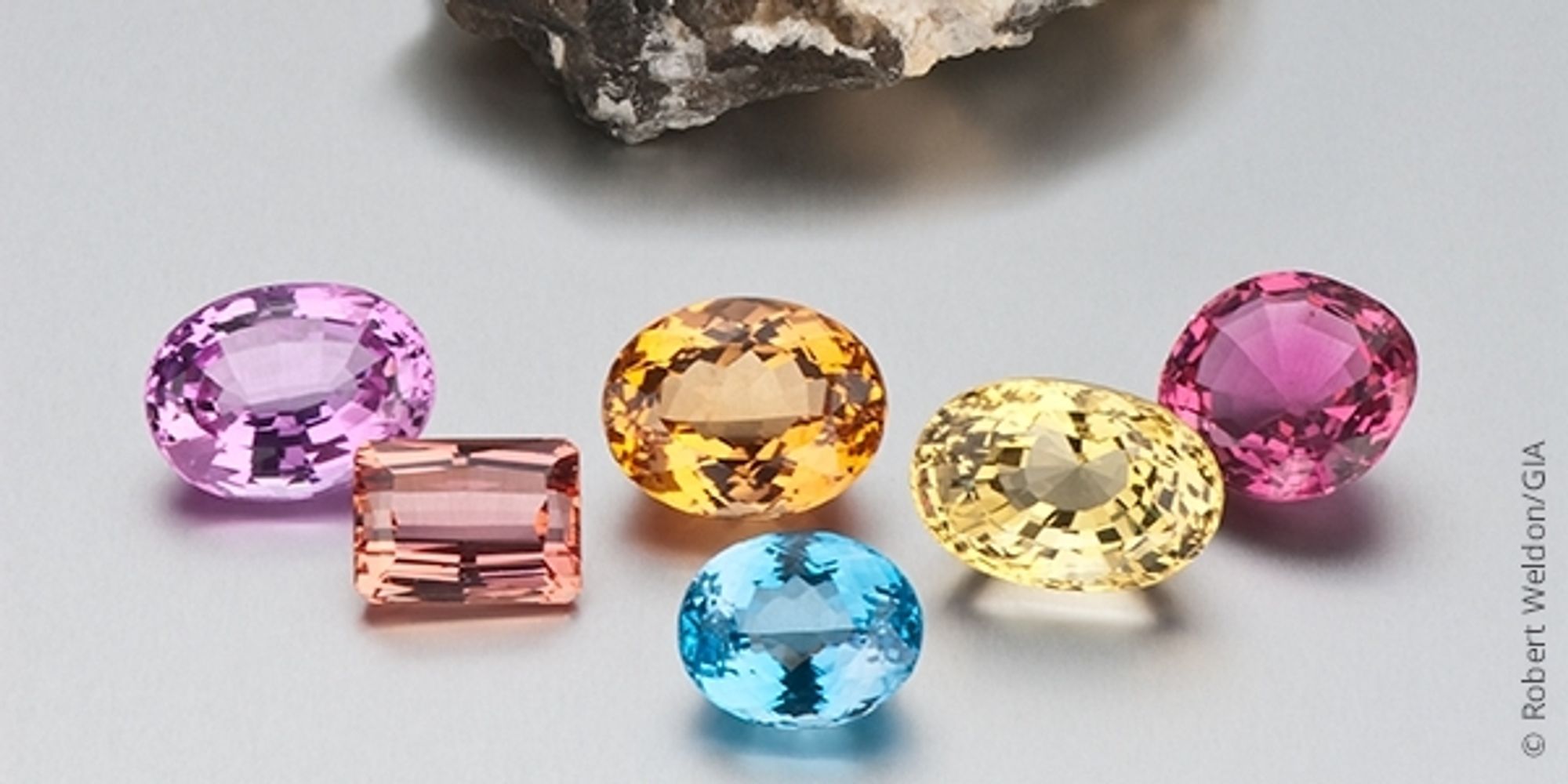 A wide variety of topaz colors and shapes cut into gemstones from the left it's purple pink orange blue yellow and dark pink or red