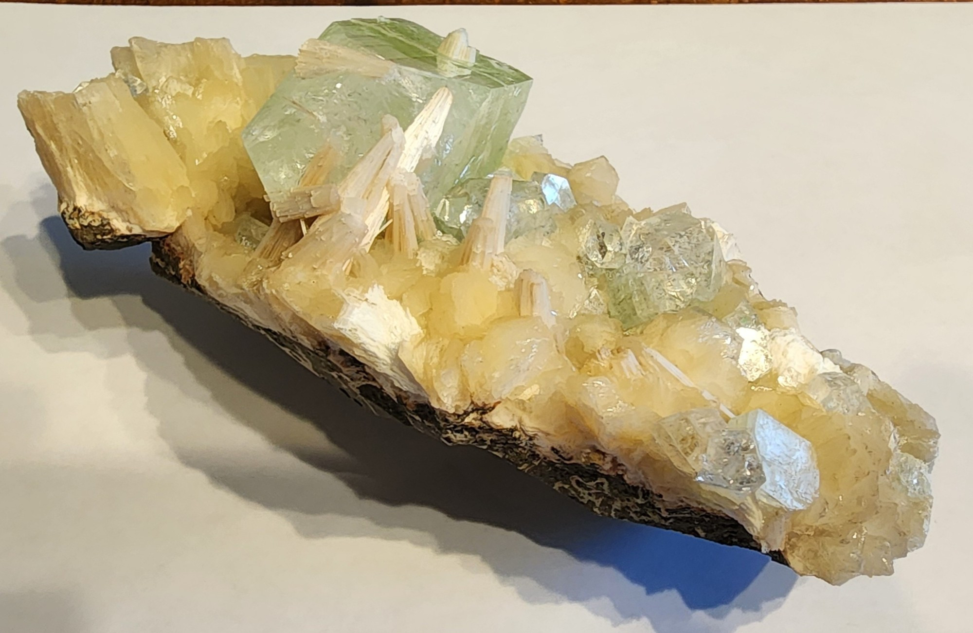 Fibrous still bite Jets above the large Crystal chunk of copper impregnated apophyllite, which is the light green coloration that you can see in the crystals there. Oblong and pointed from left to right, it is a stunning piece that shows the varied ways that Apophyllite crystals can grow as well as variations in stilibite