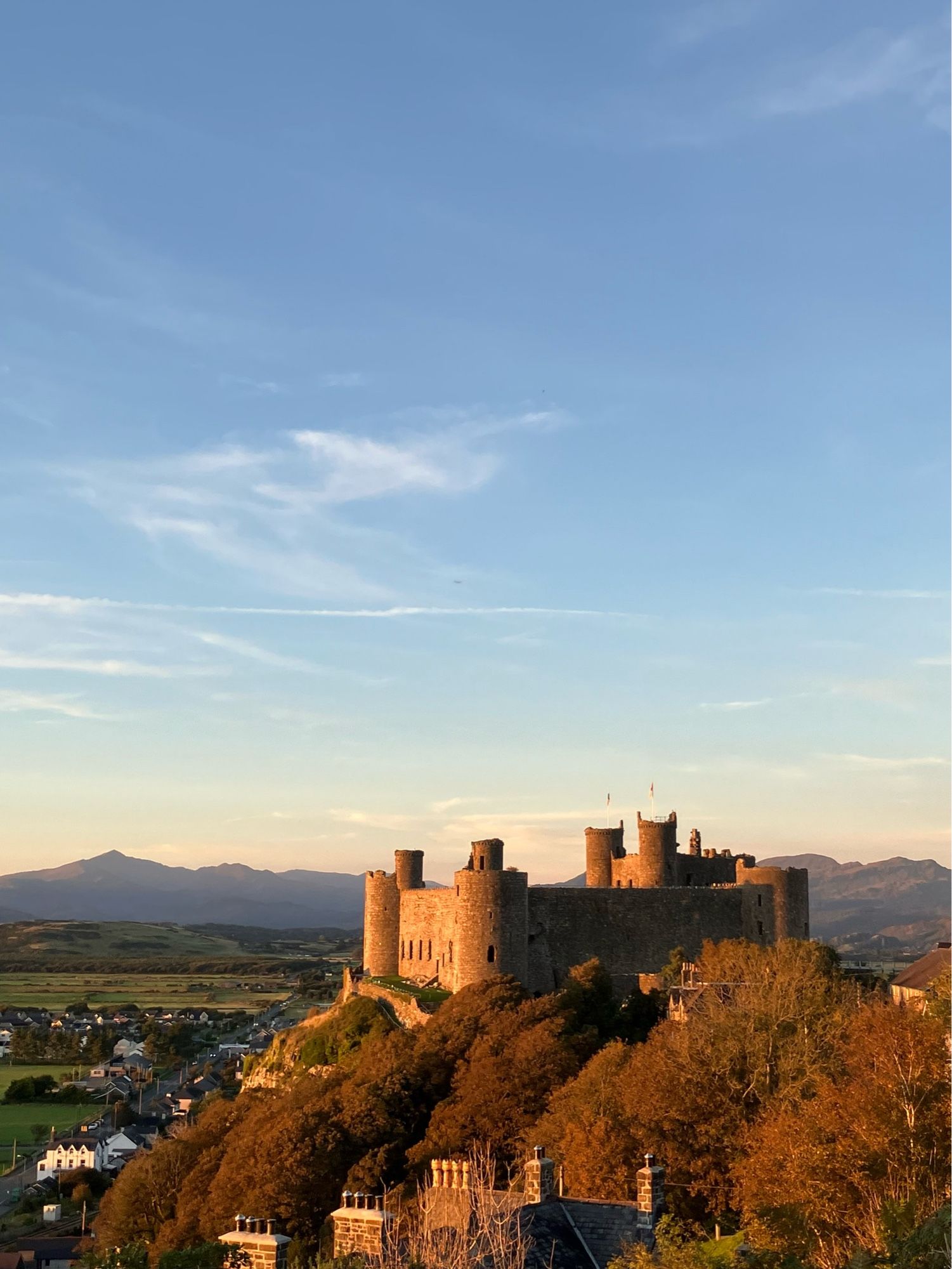 A high blue sky, fading to lemon yellow at the horizon; in the background the mountains are almost purple. The pic is dominated by the square bulk of a massive medieval castle on its huge rock, the west-facing walls golden and warm in the light of the setting sun.