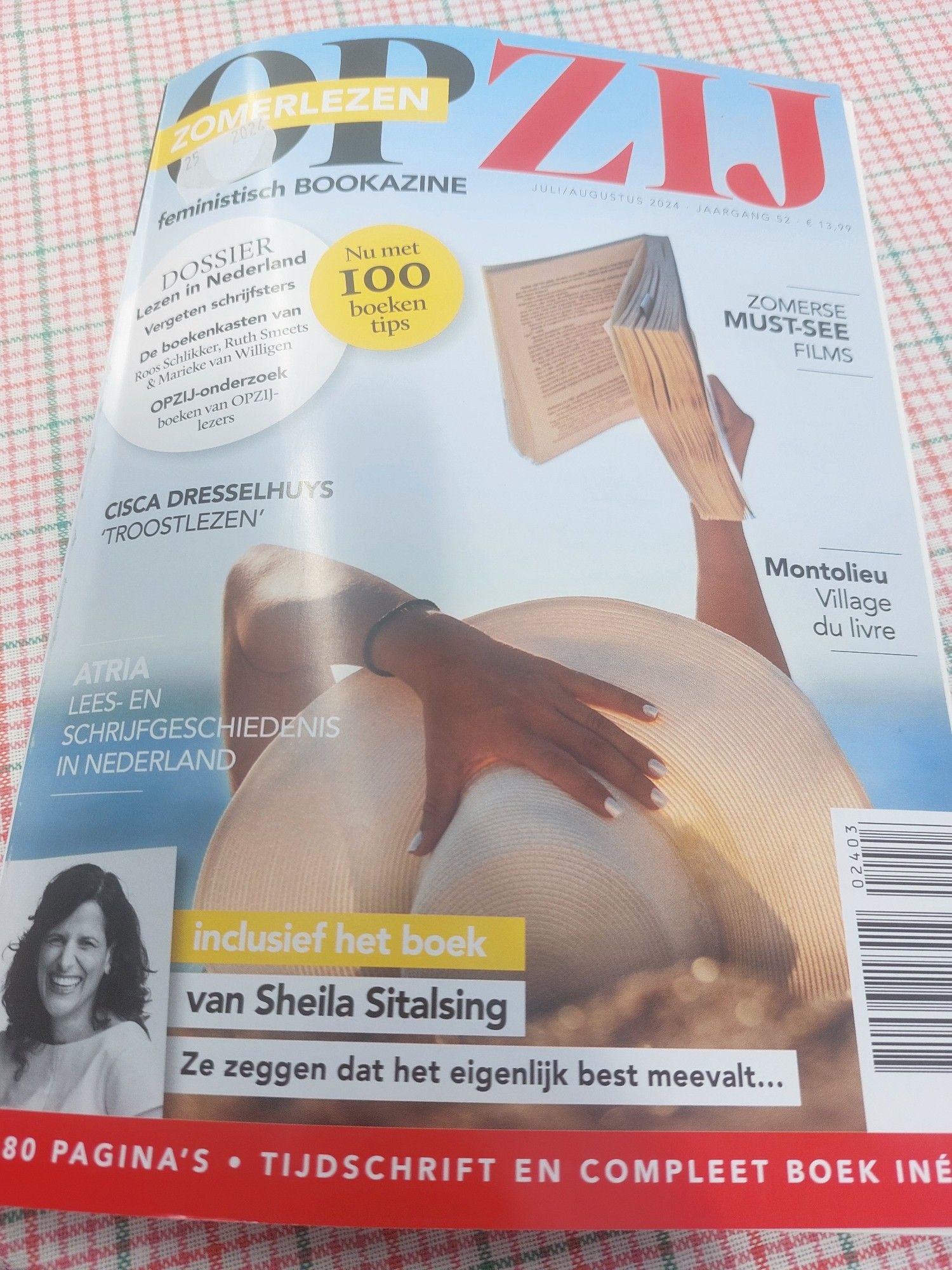 De OPZIJ is nu een BOEKAZINE, Zomer editie 2024 met het boek vol columns van Sheila Sitalsing. Vrouw ligt te lezen met een verfrommeld opengeslagen boek in d'r rechterhand.