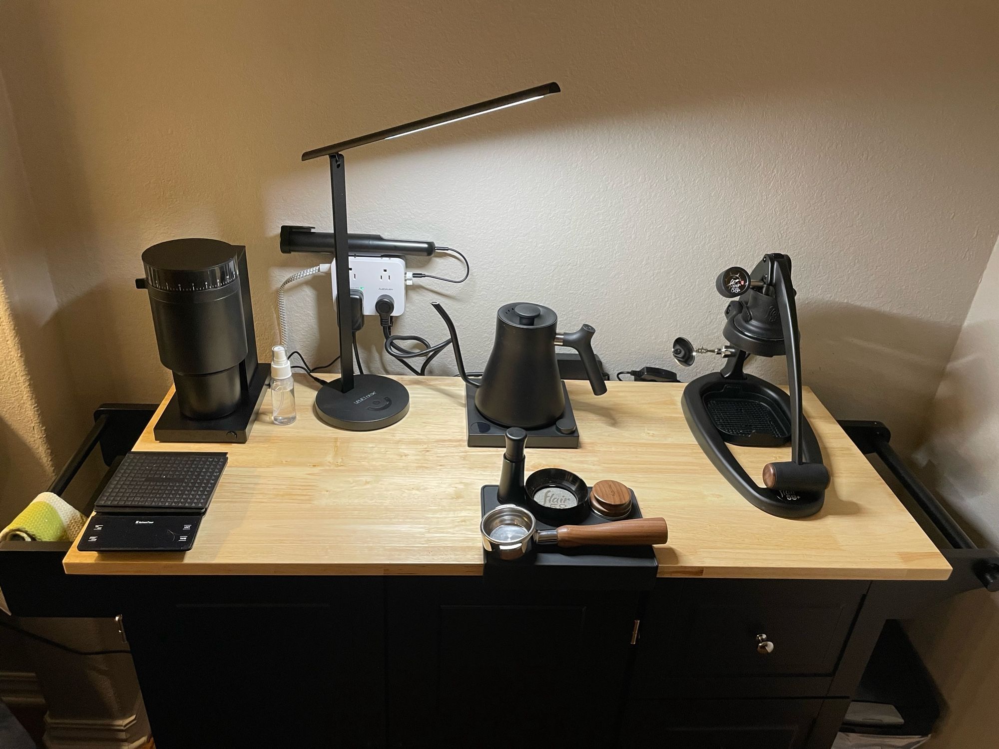 Coffee bar espresso setup with grinder and scale to the left, kettle and tamper setup in the middle and espresso maker to the right