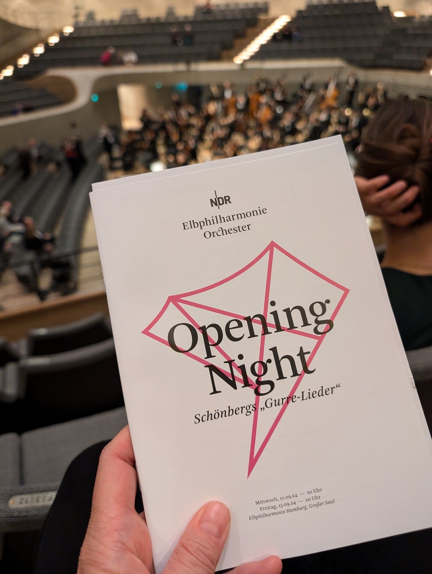 Das Programmheft der "Opening Night" des NDR Elbphilharmonie Orchesters (vor dem Hintergrund der Bühne des Großen Saals mit Teilen des Orchesters): Schönbergs "Gurre-Lieder"