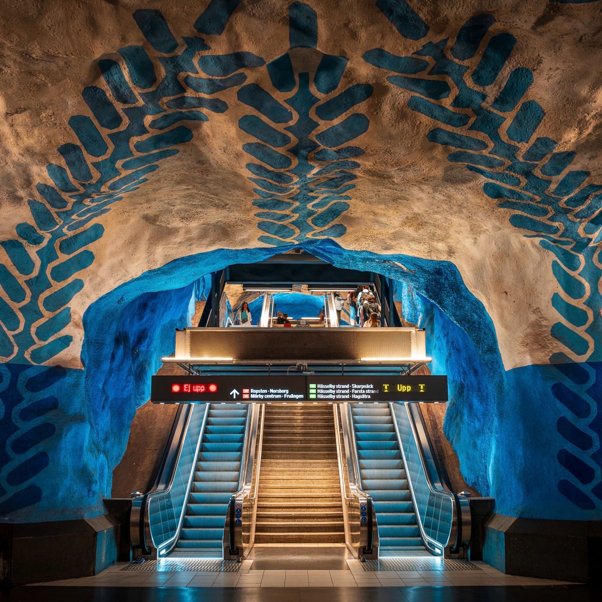 Escalators in T-Centralen station in Stockholm with a distinctive blue decoration painted onto the cave like wall.