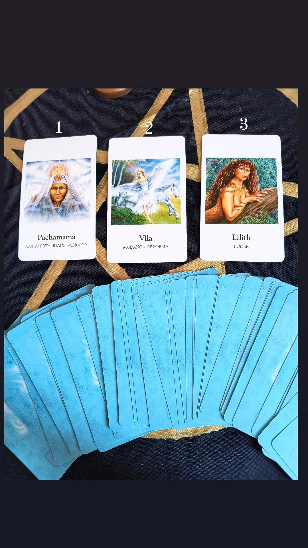 Cartas das deusas Pachamama, Vila e Lilith abertas em uma toalha preta com as demais cartas viradas para baixo e dispostas em semi círculo logo abaixo