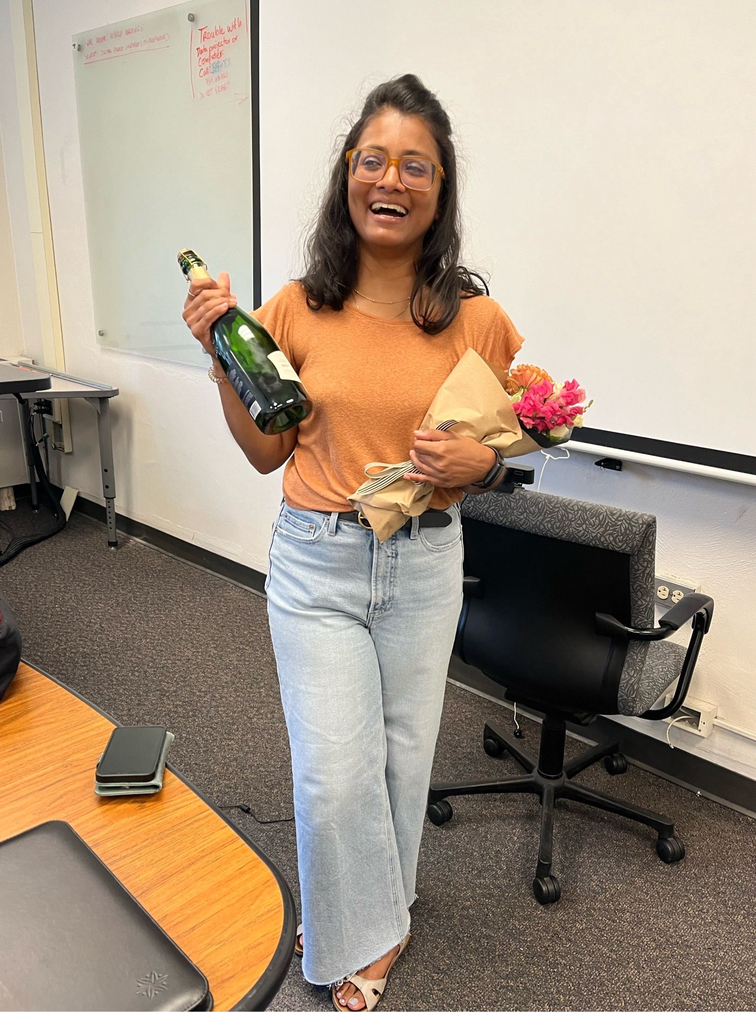 Dr Bisnath, laughing while holding her champagne and a bouquet after having successfully defender her thesis in July.