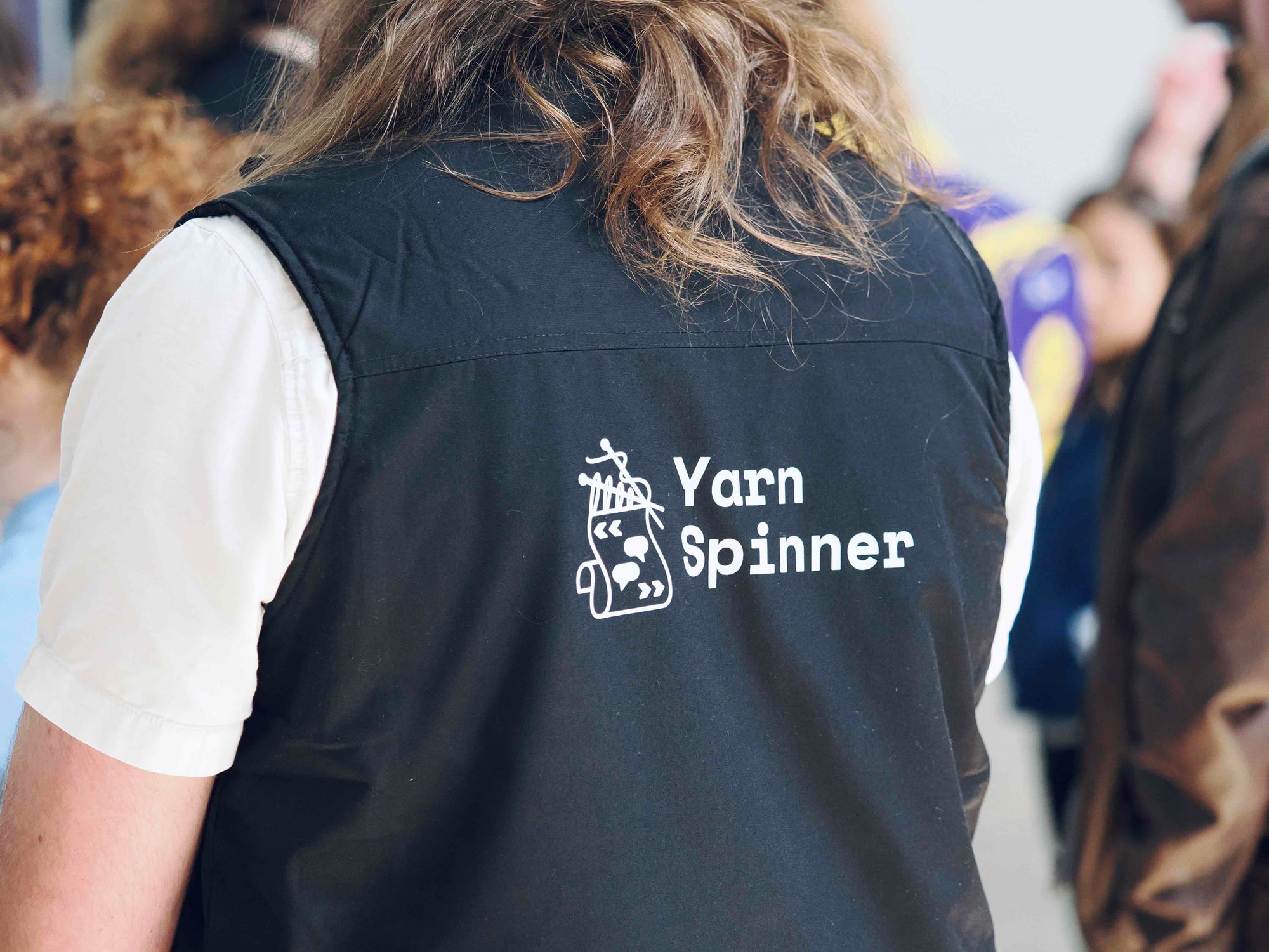 Back of a person’s black vest with the words “Yarn Spinner” on.