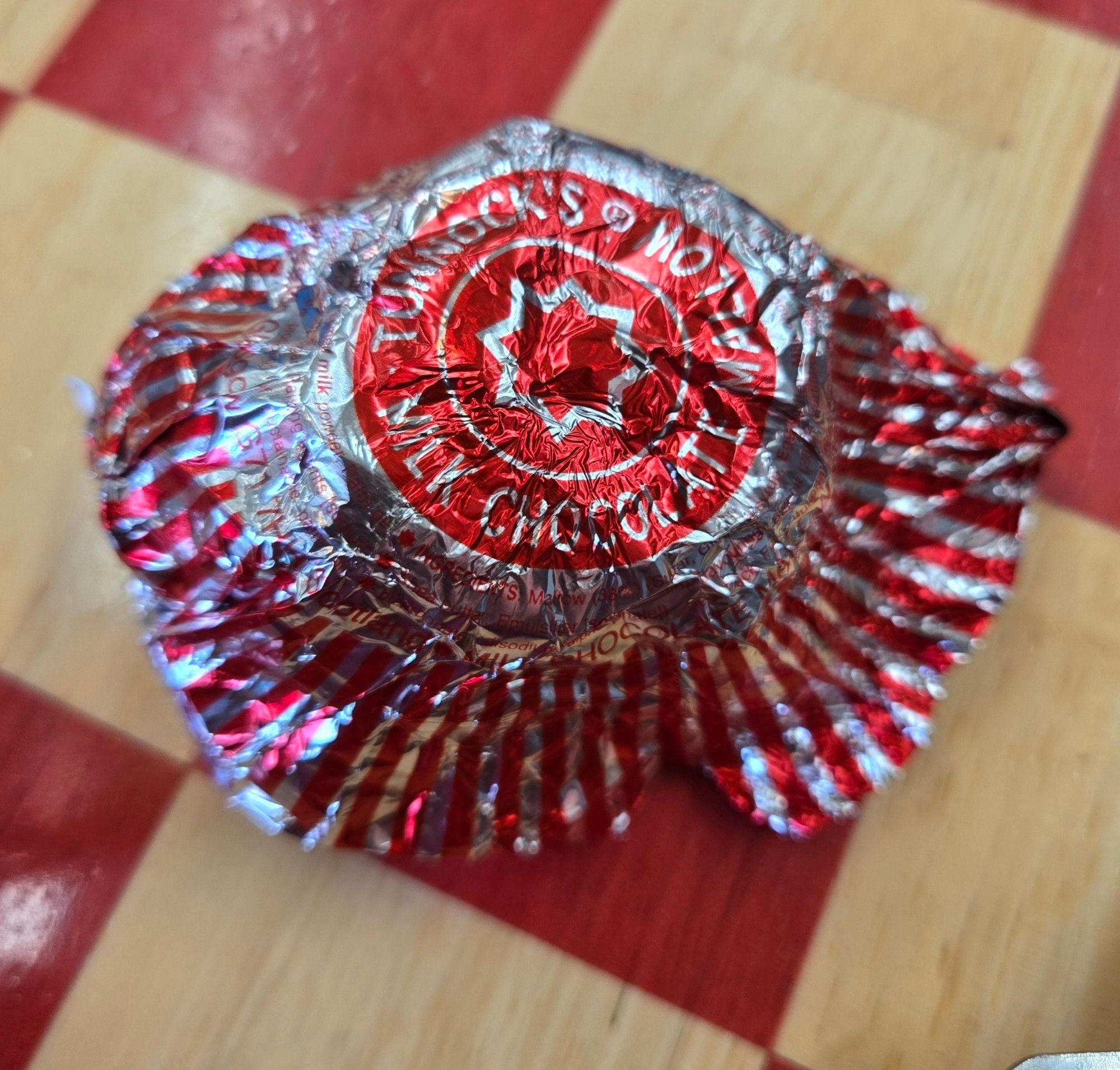 Empty Tunnock's tea cake wrapper on a red chessboard table