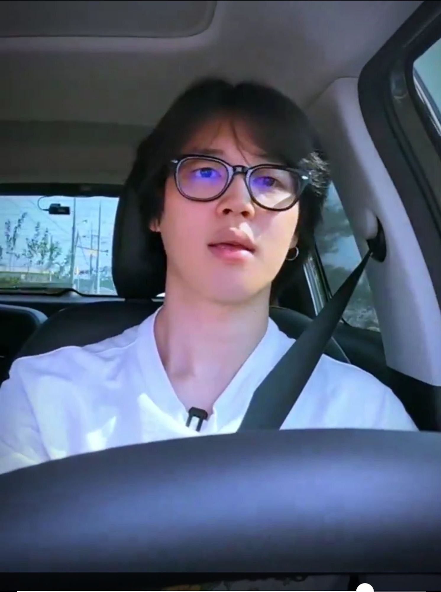 A screenshot of jimin with fluffy dark hair and glasses... driving...from ARE YOU SURE