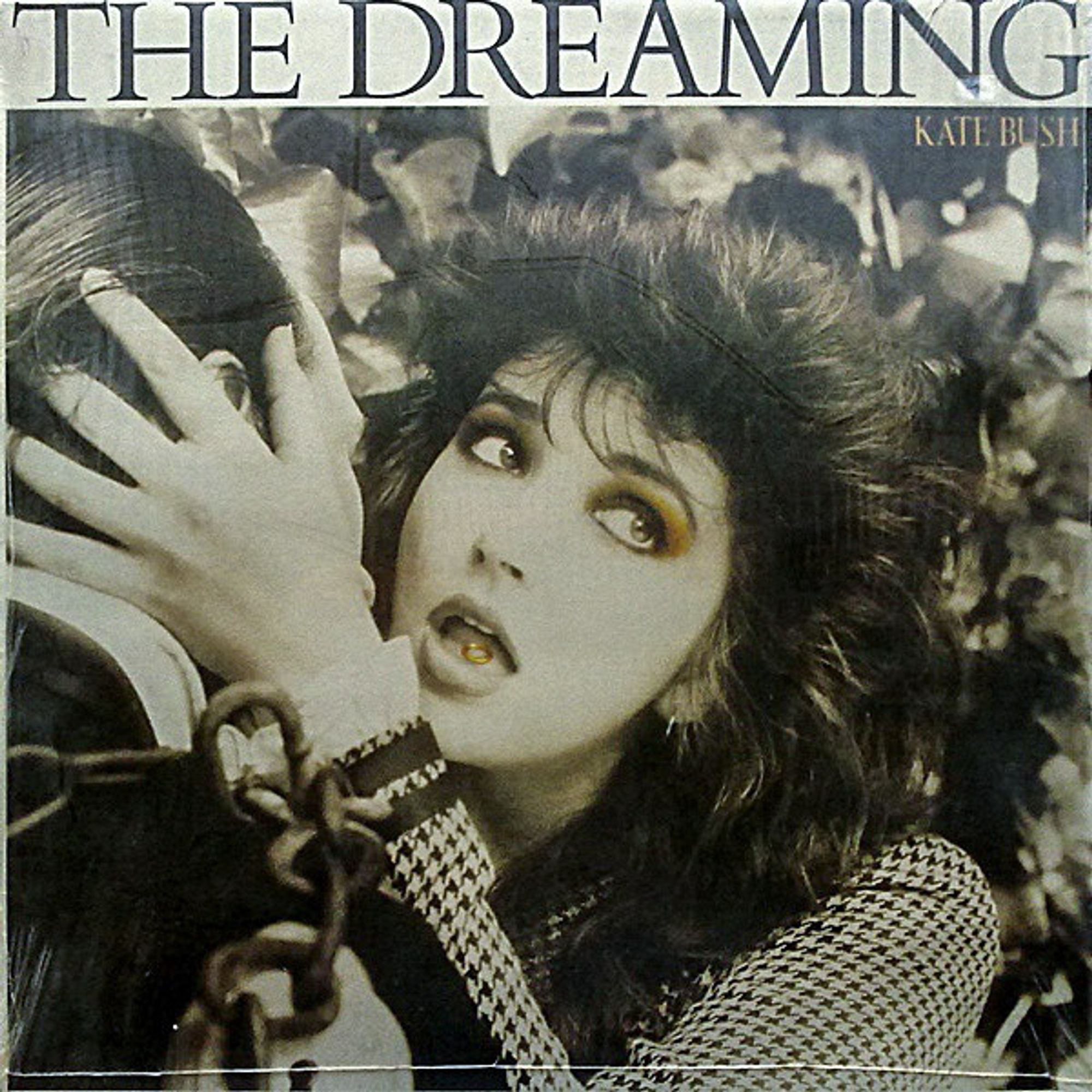 The album cover features a warm-toned, almost monochrome close view of a woman about to embrace and kiss a man who's head is turned away from us, his face further obscured by her hands either side of his head to pull him in. She has a furtive look on her face, her eyes cast aside and back to see if anyone is looking, and her mouth is slightly open showing a golden key on her tongue. The man's shoulder is wrapped in thick chain and the overall style suggests the early part of the twentieth century; this is clearly supposed to be Harry Houdini receiving the key to unlock his chains before his escapology trick. The album title is written in large text across the top with the artist name smaller and beneath.