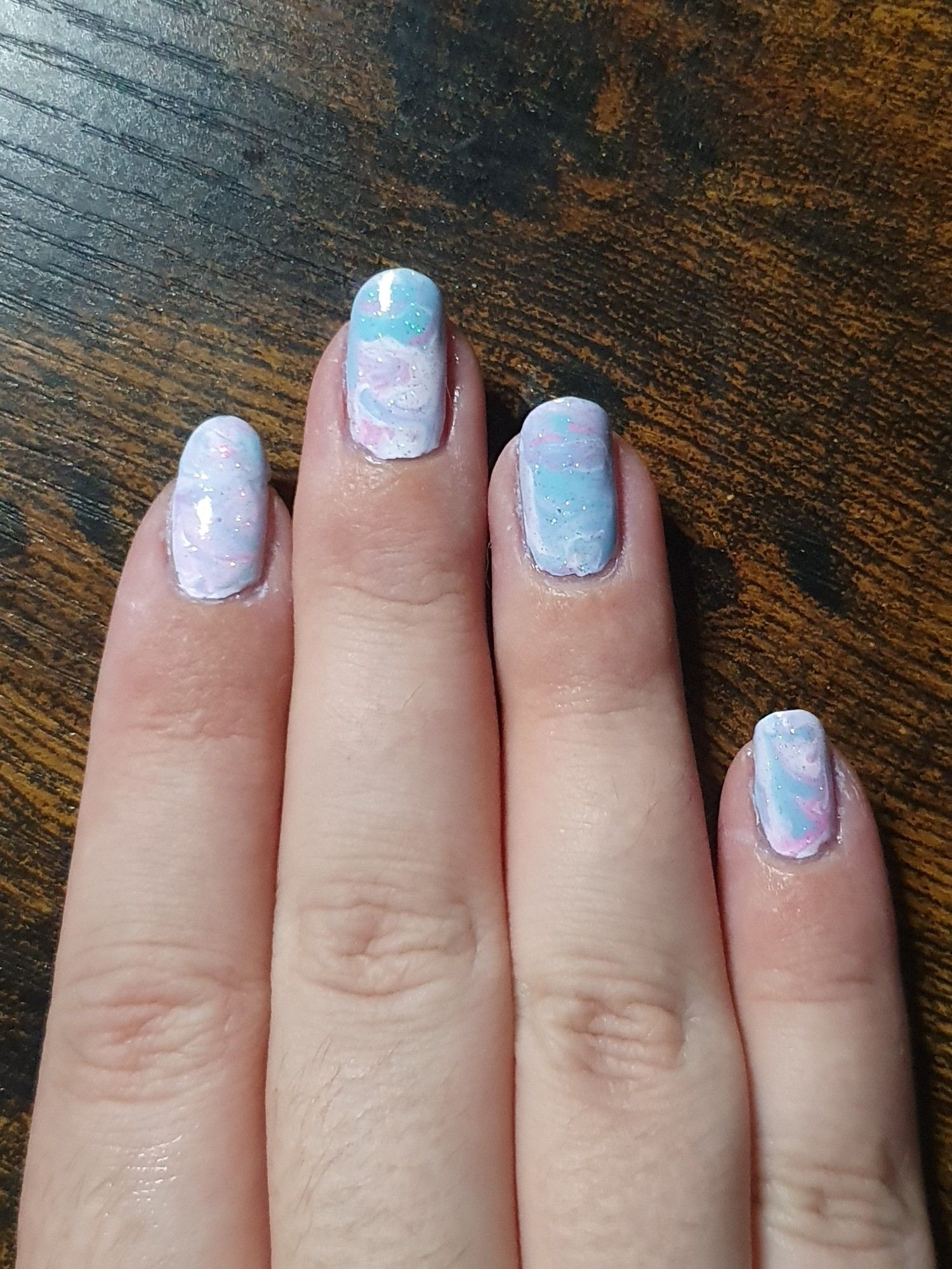 Right hand with mixed up and swirled white pink and blue nail polish