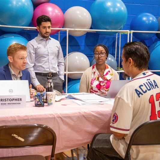 Christopher Dutot, volunteer attorney with Miller Canfield, assists an attendee of the Road to Restoration clinic hosted by LA SED in Southwest Detroit.  