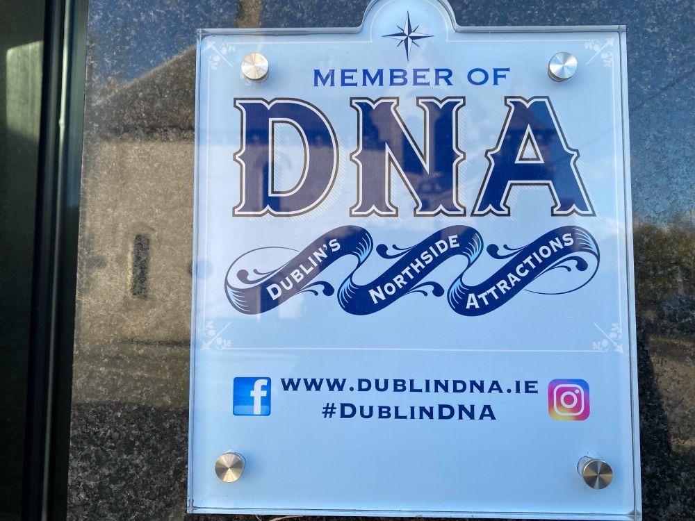 
Ein Schild, das die Mitgliedschaft bei DNA (Dublin's Northside Attractions) anzeigt, mit der Website-URL und Social-Media-Symbolen für Facebook und Instagram. Das Schild hat ein blau-weißes Farbschema mit dekorativen Elementen.



A sign indicating membership in DNA (Dublin's Northside Attractions), featuring the website URL and social media icons for Facebook and Instagram. The sign has a blue and white color scheme with decorative elements.