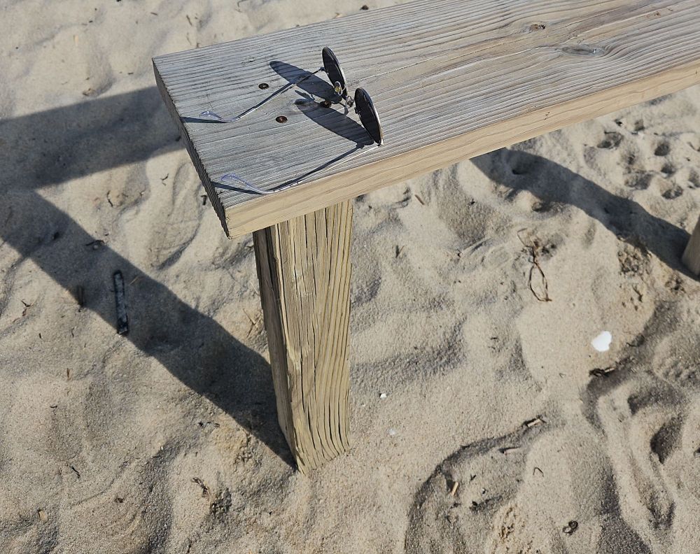 Sunglasses on a wooden bench at the beach. 