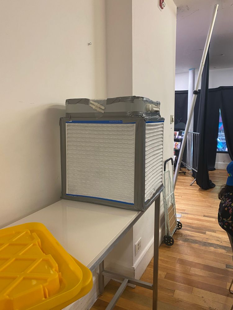 An improvised box fan filter with a box fan and four HEPA filters. The seams are sealed with duct tape.