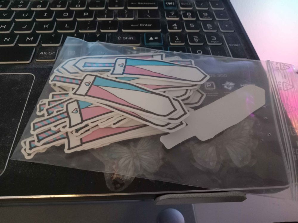 A collection of Trans colored sword stickers on a laptop
