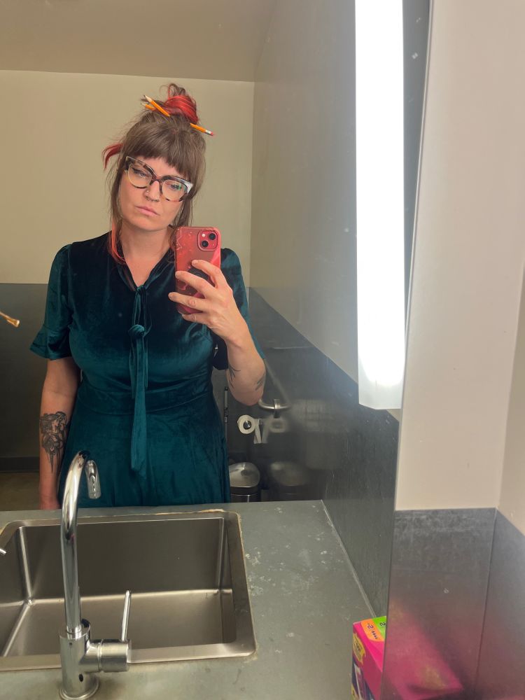 mirror selfie where i have a frown and messy bun with pencils in it