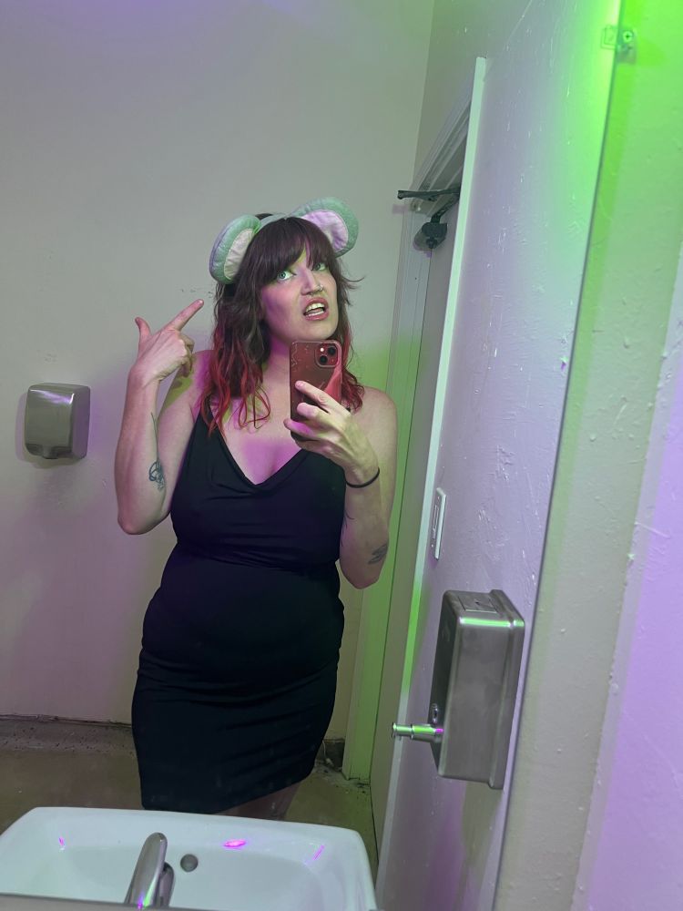 i’m wearing a low cut black dress and mouse ears, rolling my eyes and pointing to my ears. as if to say… “duh”