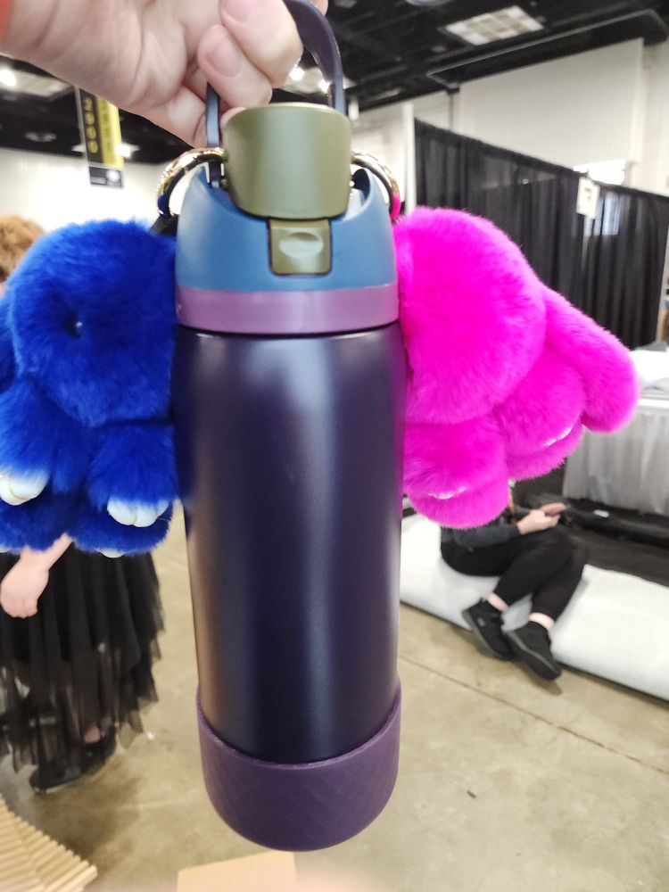 A purple water bottle with blue and pink bunny keychains.