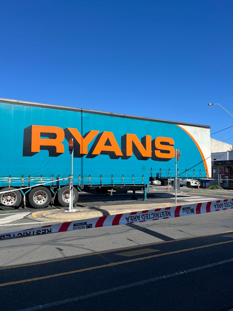 A blue truck trailer without its front, restricted area fire rescue tape in the foreground 