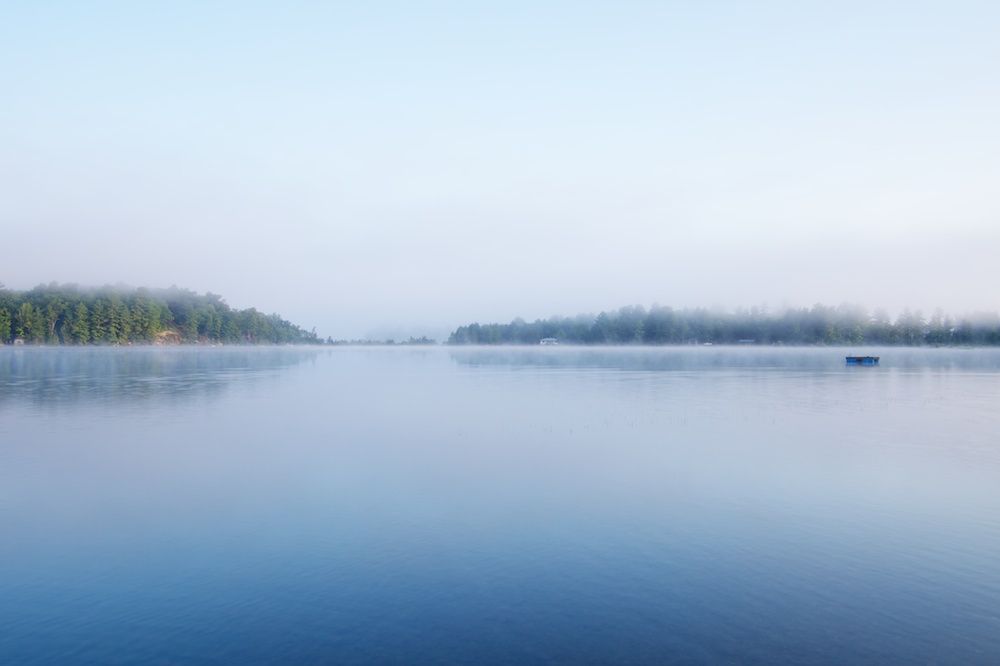 A lake in the mist, with two land masses in the distance 