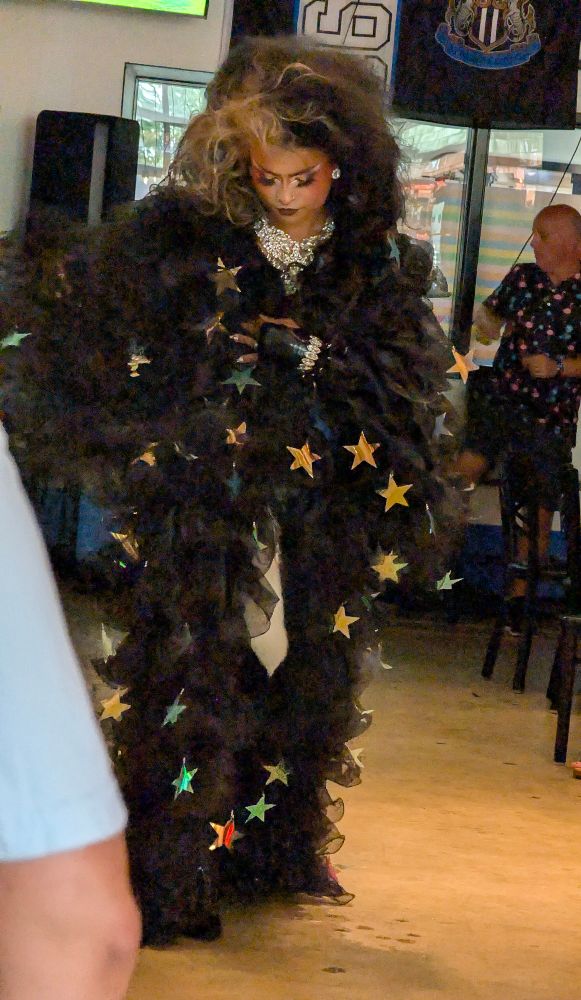 A drag performer in black ruffles and gold stars