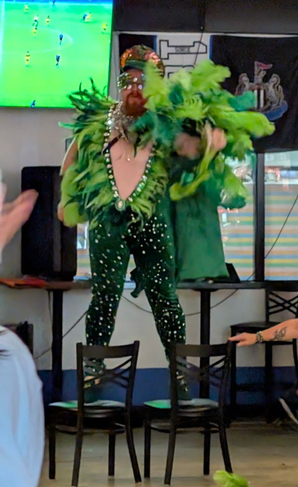 In sparkles and green feathers, Giovanni lip syncs to Elton John. While standing on chairs.