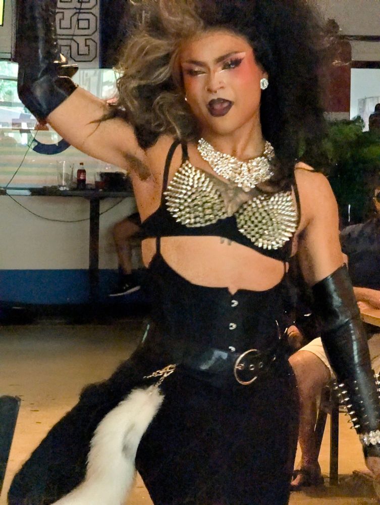 Drag performer in black and a gold studded bra