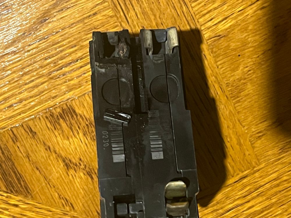 A circuit breaker that was removed from the fuse box. There are scorch marks and melted plastic visible on its connections.