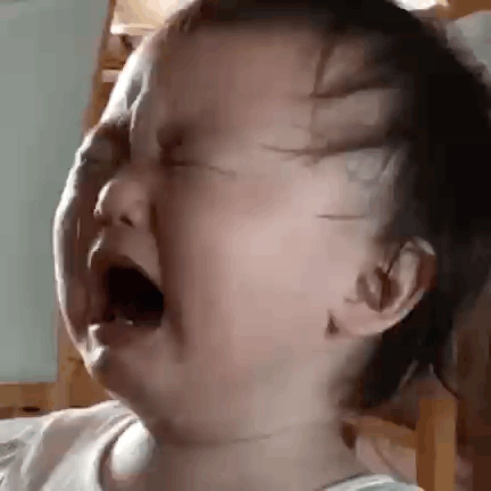 a baby is crying with his mouth open in a close up .