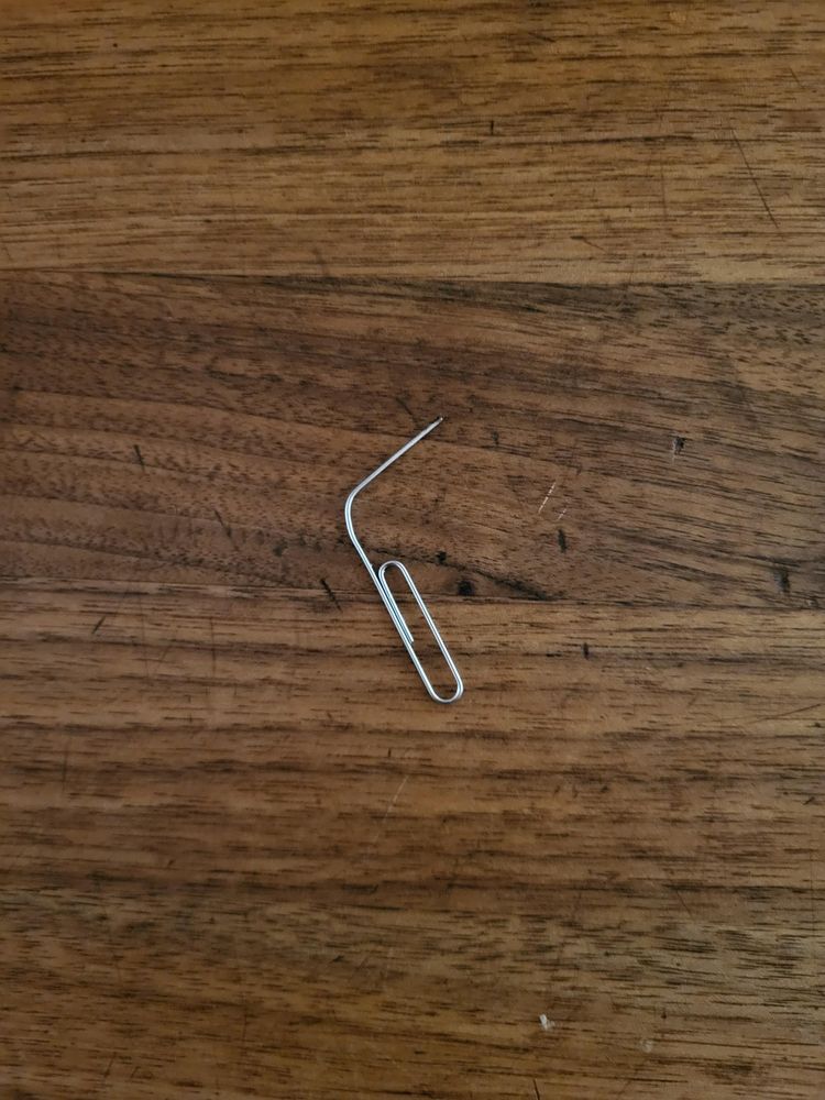 A paper clip -- the bent-wire metal oval kind -- with one end bent out about 50 degrees.

It's sitting on a dark wood countertop.