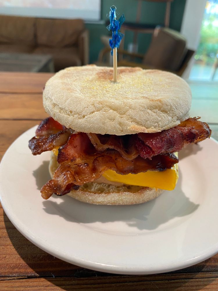 A breakfast sandwich on an English muffin. Visible are egg, cheese, and an ungodly pile of bacon. 