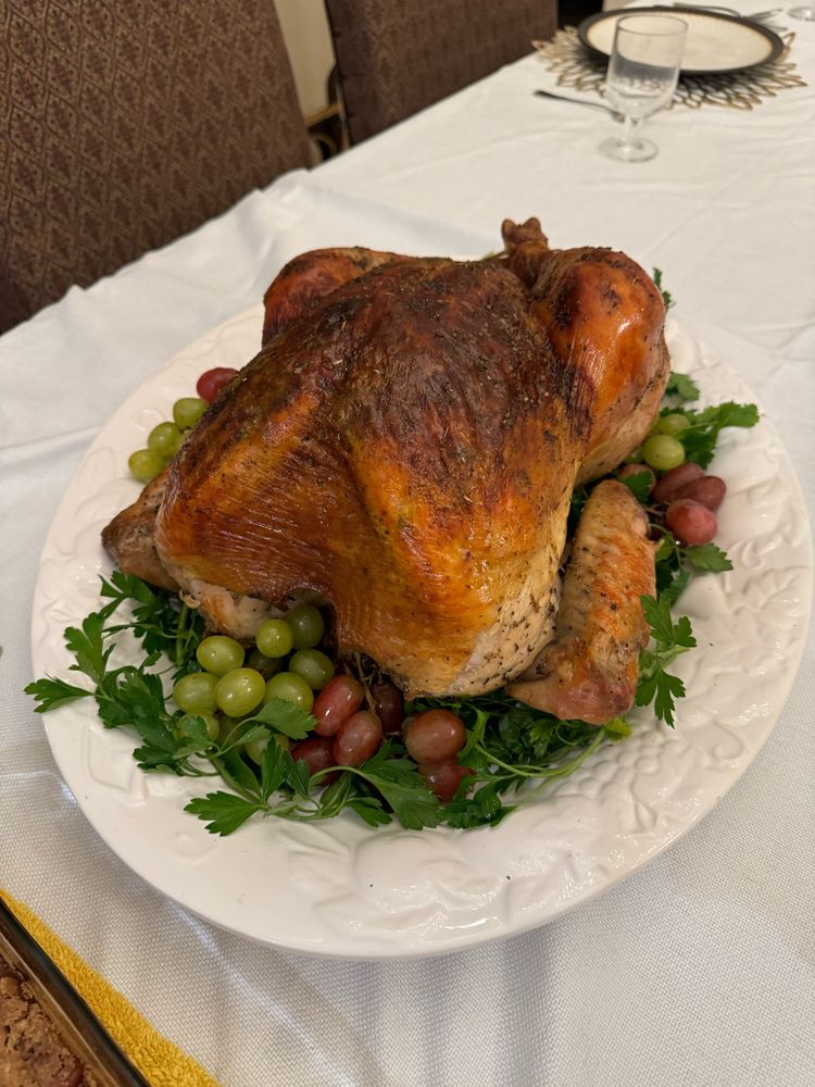 roasted turkey on a white platter with grapes and Italian parsley
