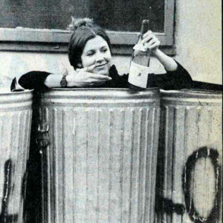 Carrie Fisher in a trash can holding an empty wine bottle 