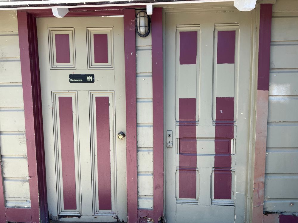 Photo of two very different doors.  Someone has tried to make them look similar by painting similar contrasting rectangles on each.